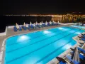 Basen hotelowy nocą, z widokiem na oświetlone miasto na horyzoncie. Idealne miejsce na relaks, jak sugerują pozytywne opinie o horizon beach.