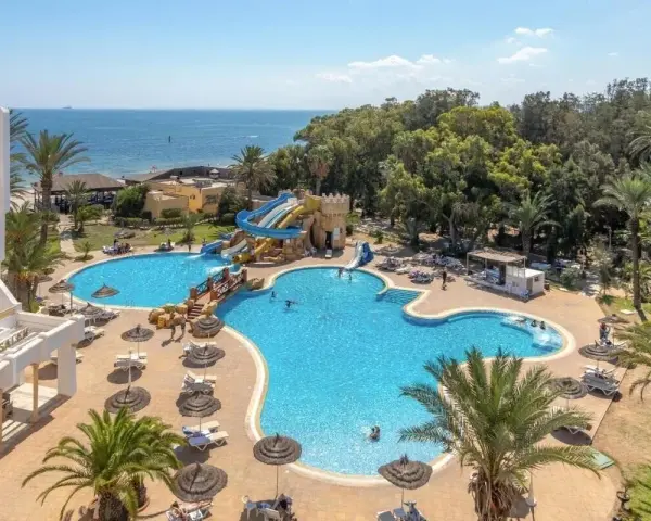 Basen z wodnymi zjeżdżalniami i palmami przy hotelu, idealne miejsce na wakacje. Wiele osób korzysta z uroków tego miejsca, co potwierdzają pozytywne marhaba club opinie.