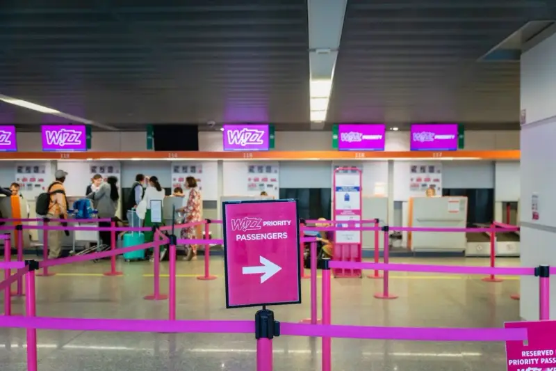 Kasa Wizz Air, gdzie pasażerowie dokonują self check-in. Różowe taśmy wyznaczają kolejkę do stanowisk odprawy.