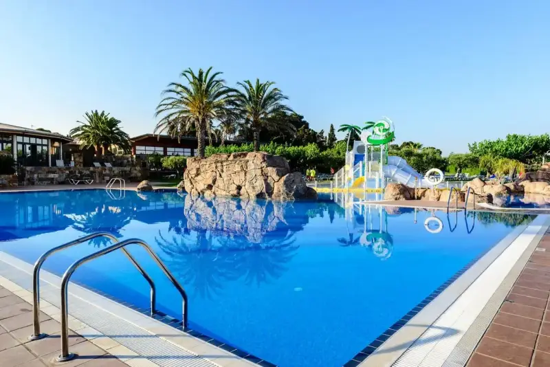 Basen w Estival Eldorado Resort z palmami i zjeżdżalniami wodnymi. Idealne miejsce na letni relaks.